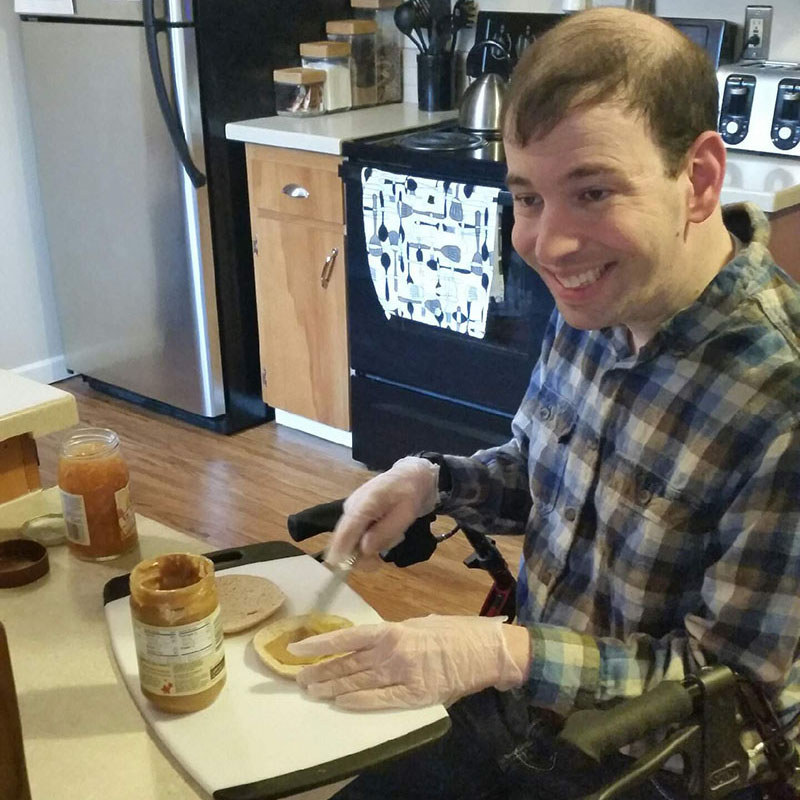 Man sitting at a kitchen table making sandwich